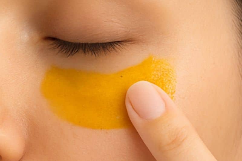 Applying turmeric under eye mask gently to skin under the eyes