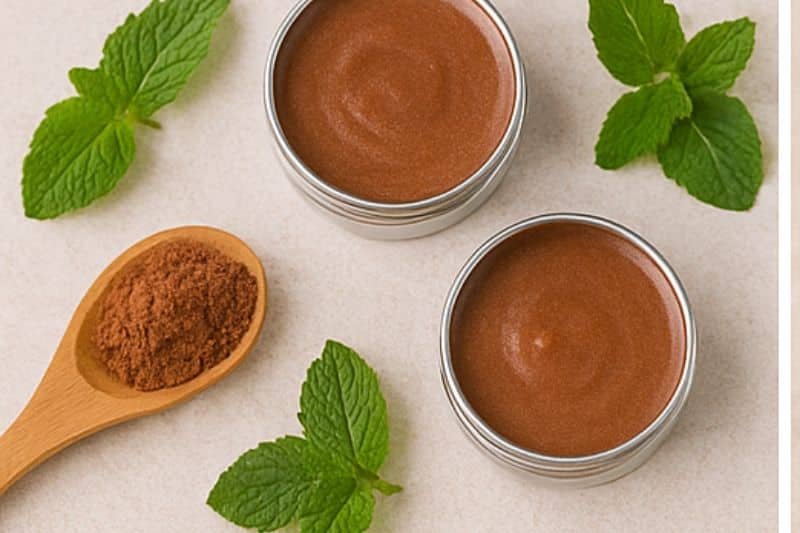Styled flat lay of finished chocolate mint lip balm with cocoa powder and mint leaves