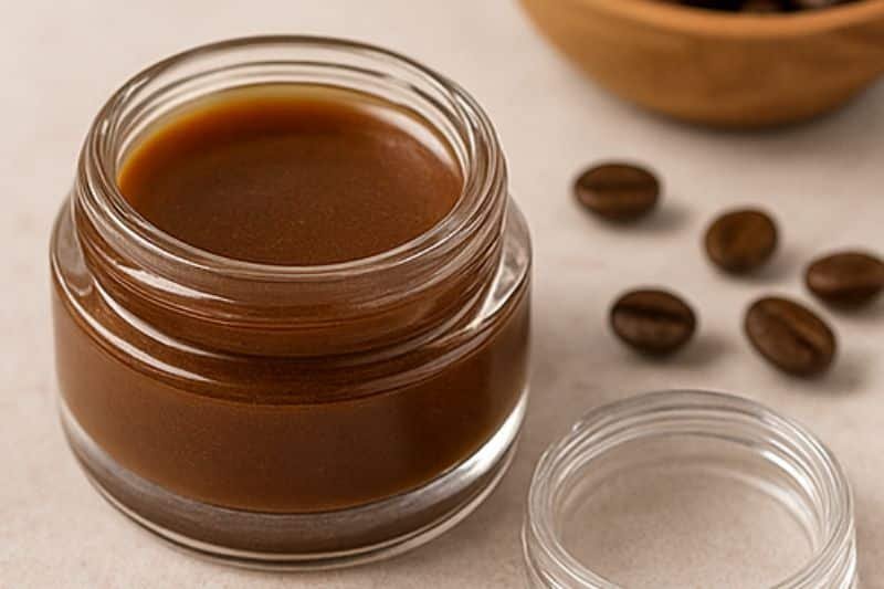 DIY coffee infused lip balm in small tins with coffee beans and a spoon of infused oil