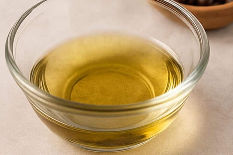 Infusing carrier oil with ground coffee in a warm water bath, then straining