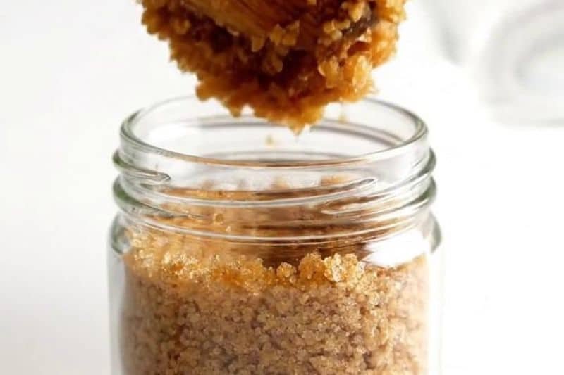 DIY brown sugar and coconut oil scrub in glass jar with open lid