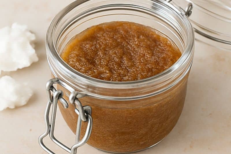 DIY brown sugar and coconut oil scrub in glass jar with open lid