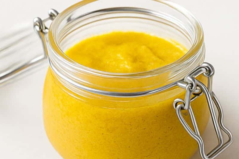 DIY turmeric and rice flour face scrub in glass jar with open lid