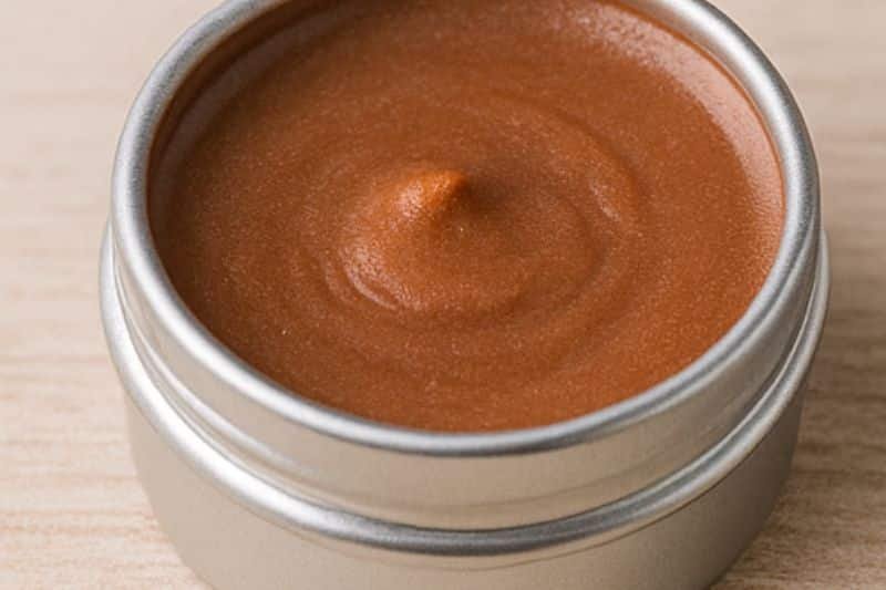 DIY chocolate mint lip balm in small tins with cocoa powder and fresh mint leaves