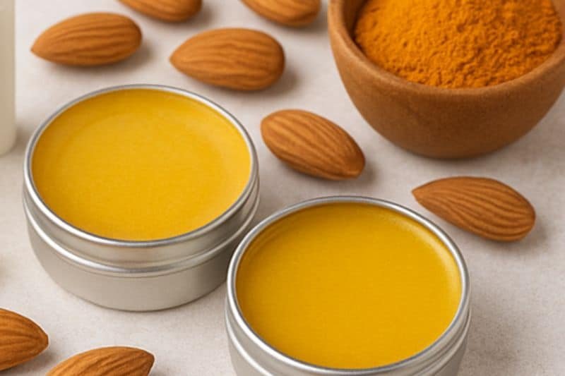 Finished turmeric lip balm tins styled with turmeric powder and almonds